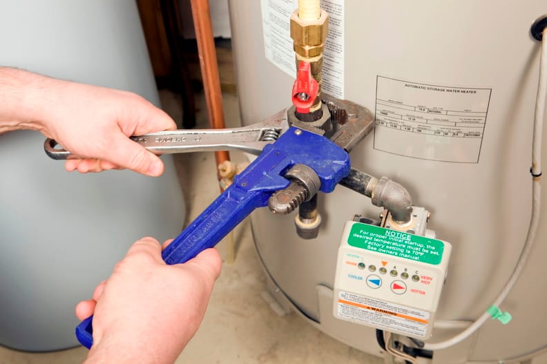 Plumber repairing water heater pipe connection in Prescott Valley, Arizona home