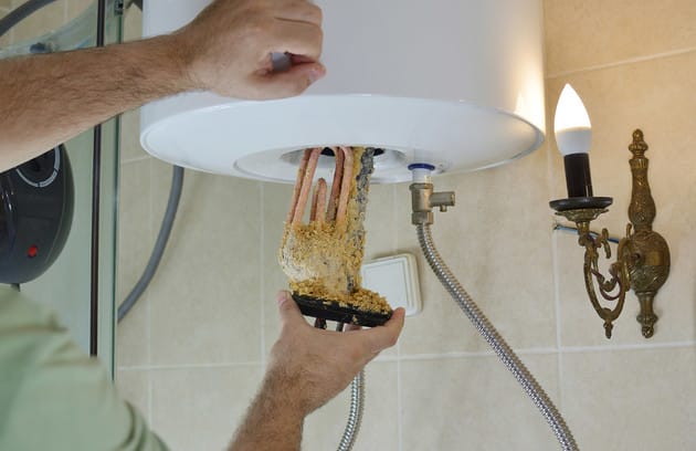Technician removing mineral buildup from a water heater in Prescott Valley