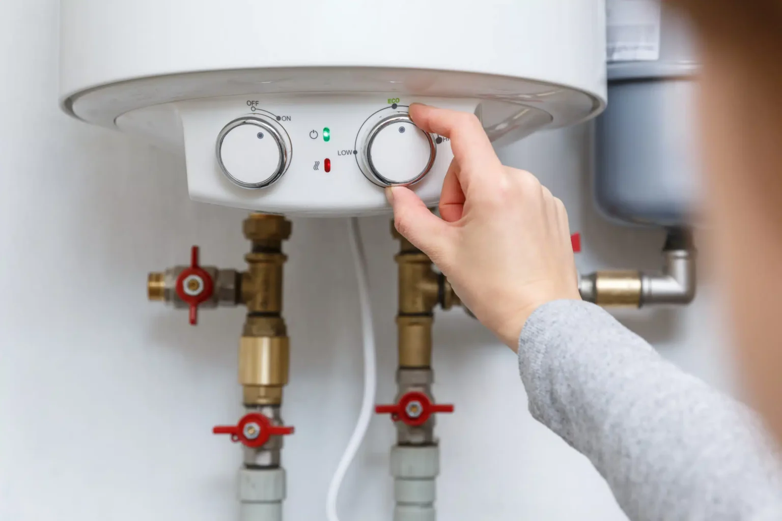 Homeowner adjusting the temperature controls on a water heater in Prescott Valley